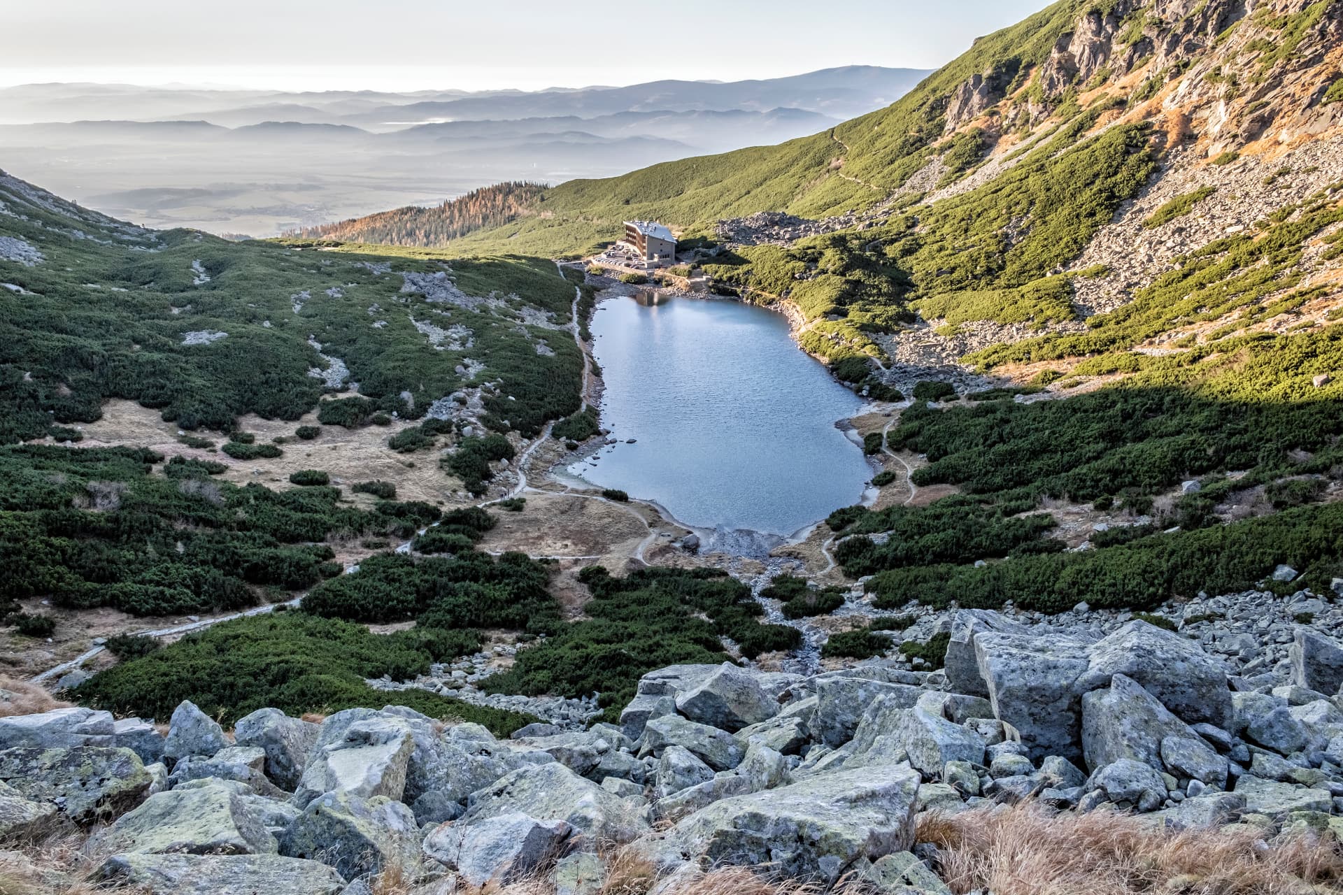 Tatranské pleso s horskou stavbou a hmlistými štítmi v pozadí